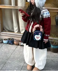Détail du sac bandoulière enfant bleu foncé avec écusson cœur en peluche et poignée rose