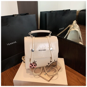Detail of cream PU leather backpack featuring cute ladybug print and HELAHE branding