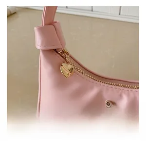 Détail du sac en cuir rose avec fermeture éclair en cœur doré et breloque papillon