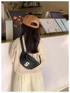 Detail of black nylon chest bag with yellow S patch and brown cotton cap with embroidery