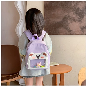 Detail of purple toddler backpack featuring a clear bear window with colorful pom-poms