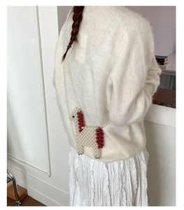 Detail of handmade pearl beaded horse-shaped crossbody mini bag with red bead accents