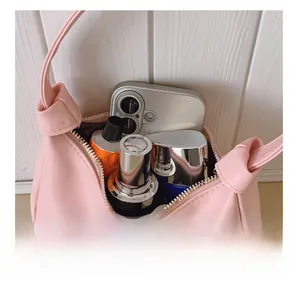 Détails de l'espace intérieur du sac en cuir rose montrant le maquillage et le téléphone