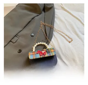 Close-up of mini plaid bag featuring a faux pearl handle and metal chain strap