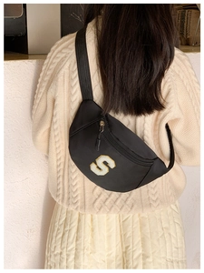 Detail of black nylon kids chest bag featuring yellow S letter embroidery and adjustable strap