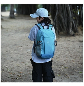 Outdoor view of a blue kids hiking backpack with side mesh pocket and mountain logo