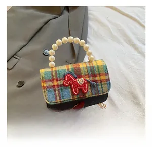 Detail of plaid fabric and denim patchwork with pearl handle and horse embroidery