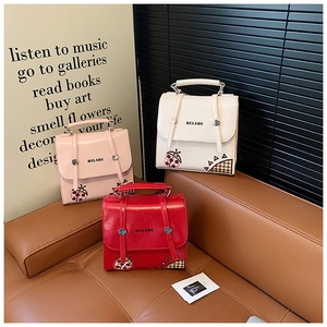 Detailed view of glossy leather handbags in pink, white, and red with ladybug motifs