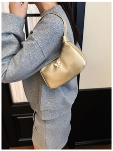 Détail d'un sac à bandoulière doré brillant pour enfant avec un ornement papillon blanc