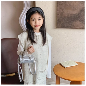 Detail of silver cylindrical toddler bag with adjustable strap and top handles