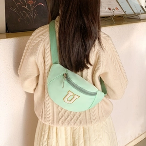 Sac de poitrine enfant vert menthe avec broderie lettre U porté par un enfant