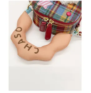 Détail du sac en tissu écossais coloré avec poignée ondulée et tirette en cuir rouge