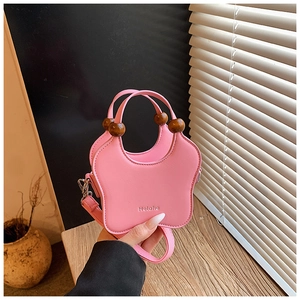 Detail of pink butterfly bag featuring wooden bead handles and detachable shoulder strap