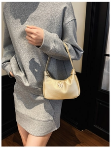 Détail d'un sac à épaule doré avec un ornement décoratif en forme de papillon blanc