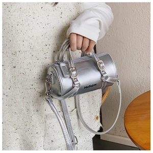 Detailed close-up of a mini silver cylinder bag with metal buckles and logo text