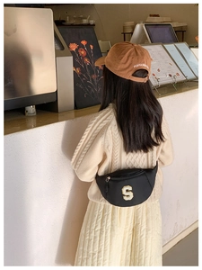 Detail of child's black chest bag with 'S' towel embroidery and brown baseball cap back view