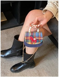 Detail of a mini plaid crossbody bag with a pearl handle and a red horse embroidery
