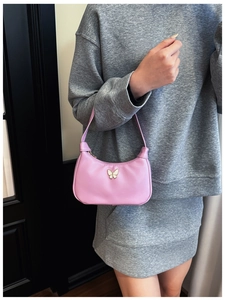 Détail du sac rose pour enfant avec boucle papillon blanche sur une tenue grise