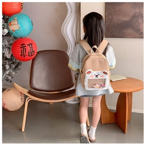 Detail of cute bear-shaped front pocket with transparent PVC window on a khaki kids backpack