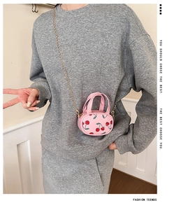 Detailed view of pink mini bag with cherry print and golden chain strap for kids