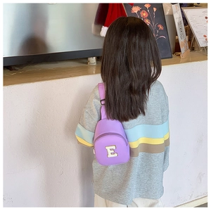 Rear view of a child wearing a purple crossbody chest bag with embroidered letter E detail