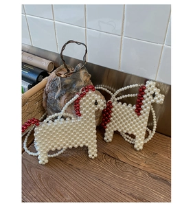 Detail of horse-shaped pearl woven crossbody bag with red bead accents and long strap