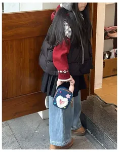 Détail du sac bandoulière enfant en denim foncé avec écussons en peluche cœur et étoile