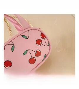 Close-up of pink mini bag featuring cherry prints and golden metal chain strap