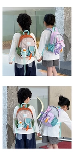 Detailed view of color-block kids backpacks with cute plush charms and buckle straps