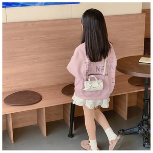 Close-up of white mini barrel bag for kids featuring Hellejm logo and leather texture