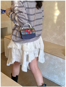 Detail of mini plaid crossbody bag with red horse patch and elegant pearl handle
