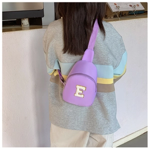Detail of purple children's chest bag featuring a white towel embroidered letter E patch