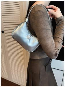 Sac hobo argenté avec logo papillon en métal présenté dans un décor de style de vie