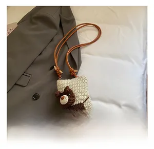 Detail view of a handmade crochet puppy shoulder bag on grey suit background