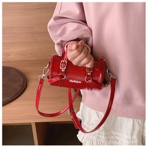 Detail of red patent leather cylinder bag with Hellojm lettering and silver hardware