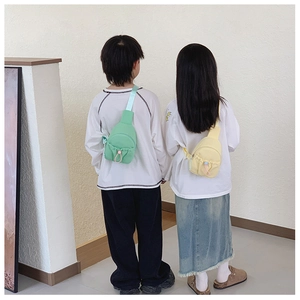 Rear view of kids wearing adjustable green and yellow nylon chest bags with drawstrings
