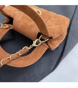 Close-up of brown suede crossbody bag with gold chain strap and quilted stitching