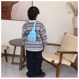 Rear view of a child wearing a light blue crossbody chest bag with adjustable strap