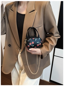 Mini cherry print crossbody bag for kids with gold chain strap shown on a model