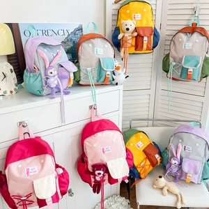 Close-up of contrast color kids' backpack with cute plush dolls and woven drawstring detail