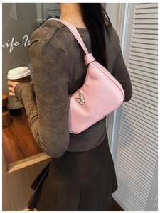 Détail du sac à bandoulière en similicuir rose avec breloque papillon et bandoulière nouée