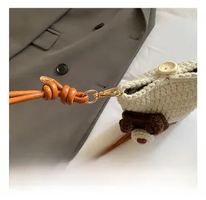 Detail of crochet dog bag showing handmade wooden button and golden metal swivel hook