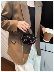 Close-up of mini black cherry pattern bag with gold chain strap on a child model