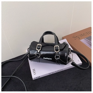 Close-up of black patent leather cylinder bag featuring glossy finish and silver hardware