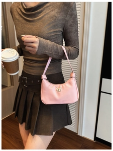 Gros plan d'un sac hobo rose avec boucle papillon dorée porté par un mannequin