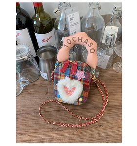 Détail du sac à carreaux avec application de cœur en peluche et poignée rose rembourrée