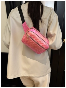Détail d'un sac bandoulière tissé rose avec trois fermetures éclair dorées au dos