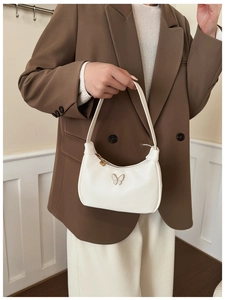 Détail d'un sac à main crème pour enfant avec nœud et fermeture cœur doré chic