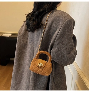 Detail of brown velvet quilted crossbody bag with gold metal buckle and chain strap