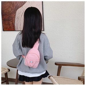 Detailed back view of a pink nylon kids crossbody chest bag shown on a young model